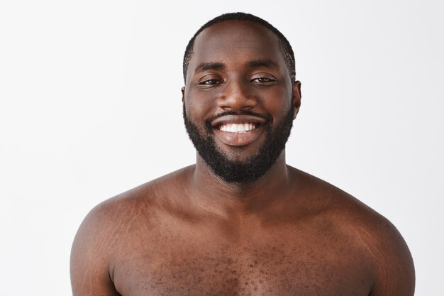 Beau jeune homme posant contre le mur blanc