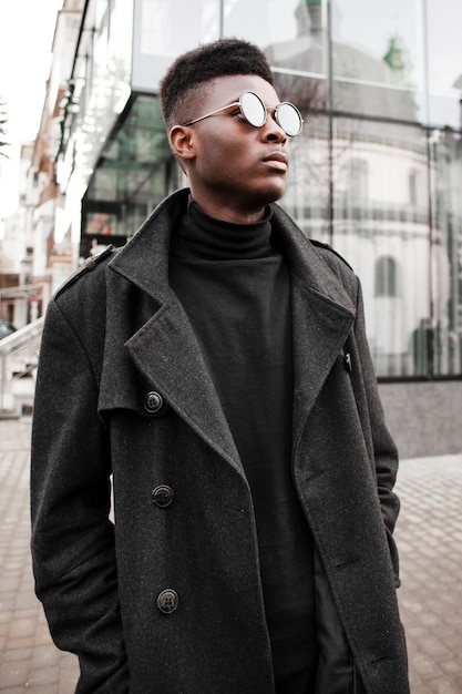 Beau jeune homme posant avec des lunettes de soleil