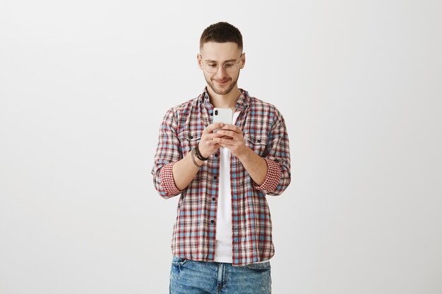 Beau jeune homme posant avec son téléphone