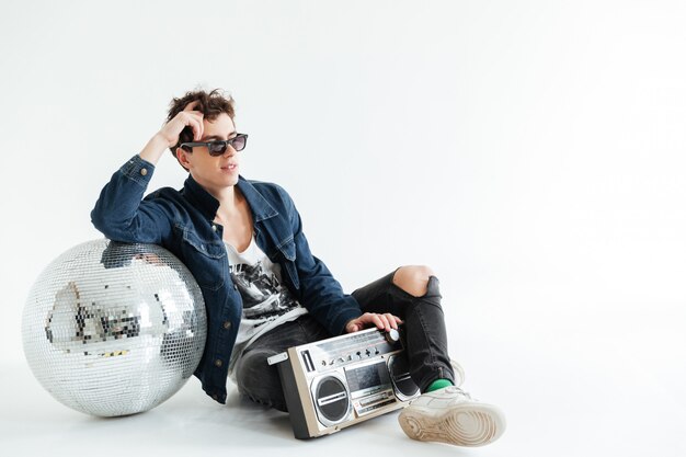 Photo gratuite beau jeune homme près de boule disco et boombox