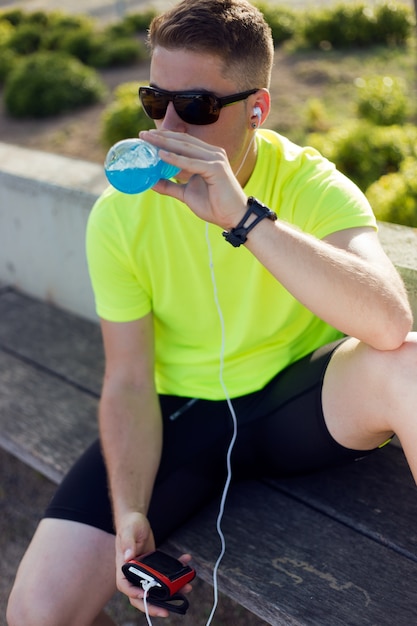 Photo gratuite beau jeune homme qui boit après la course.