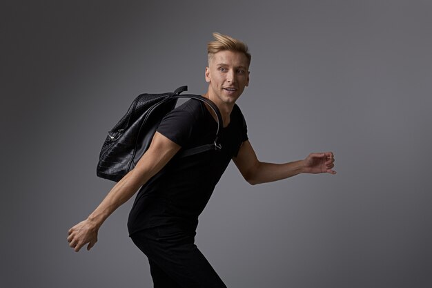 Beau jeune homme qui court avec un sac à dos sur les épaules