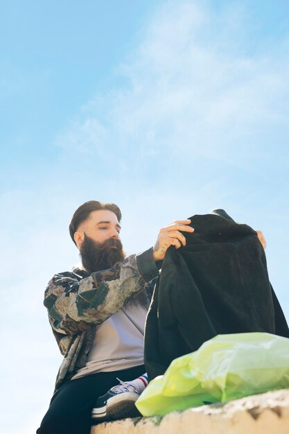 Beau jeune homme regardant nouvelle veste assis sous le ciel