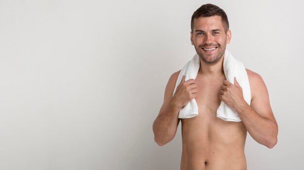 Beau jeune homme avec une serviette sur les épaules en regardant la caméra sur fond blanc