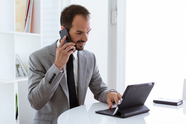 Beau jeune homme travaillant avec tablette numérique au bureau.