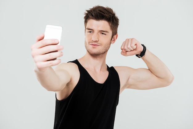 Beau jeune sportif avec téléphone faire selfie