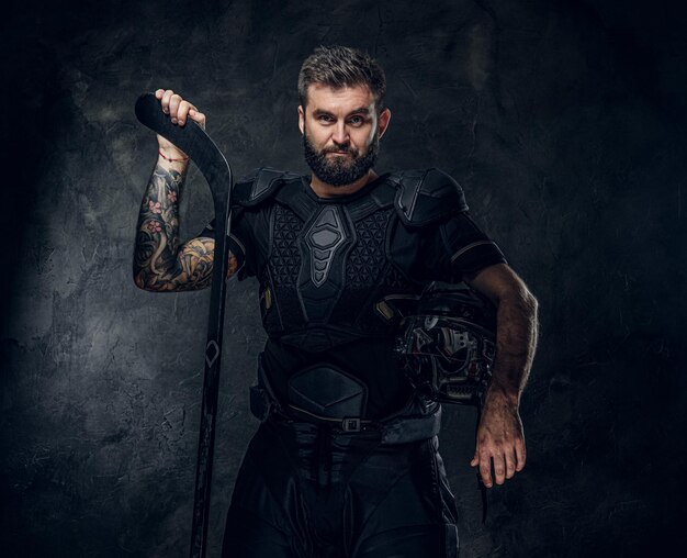 Beau joueur de hockey tatoué en uniforme pose pour le photographe.