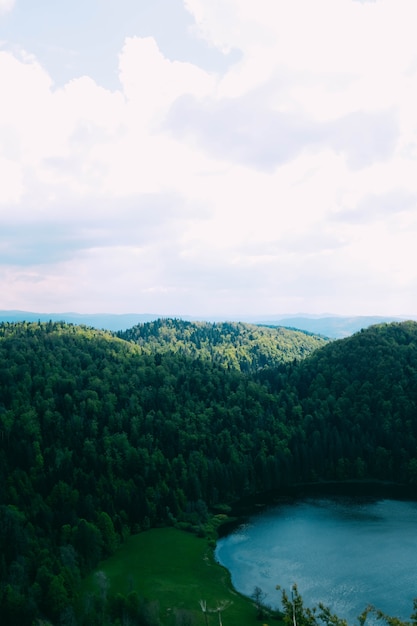 beau lac entouré de collines couvertes d'arbres sous le ciel nuageux