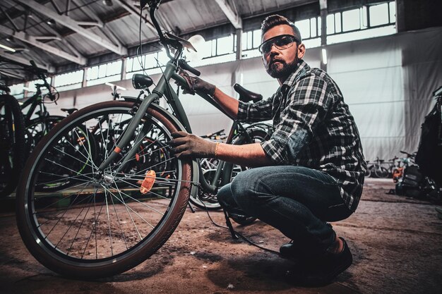 Un beau mâle diligent en lunettes de soleil répare des pneus pour un client occupé.