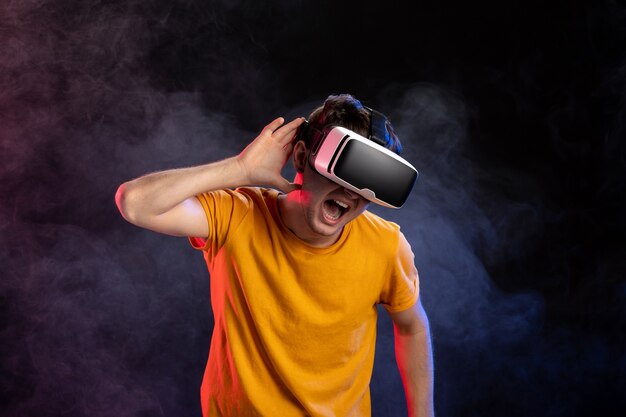 Beau mâle portant un casque de réalité virtuelle sur une surface sombre