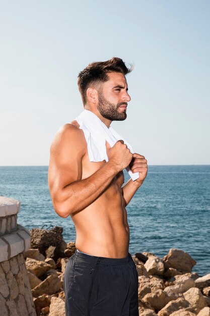 Beau mâle sportif ayant une pause après une séance d'entraînement intense