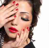 Photo gratuite beau mannequin avec des ongles rouges, des lèvres et un maquillage créatif pour les yeux - isolé sur un mur blanc