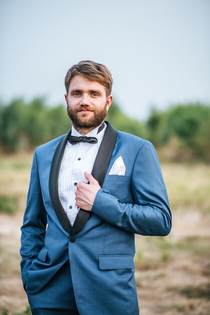 Beau marié en costume de mariage affichant dans le parc