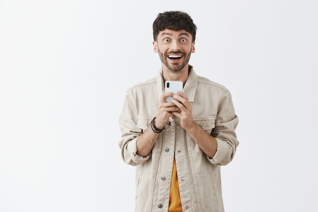 Beau mec barbu élégant posant contre le mur blanc