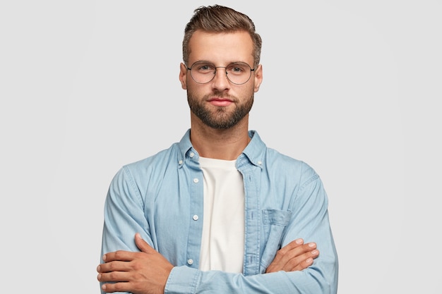 Beau mec barbu posant contre le mur blanc