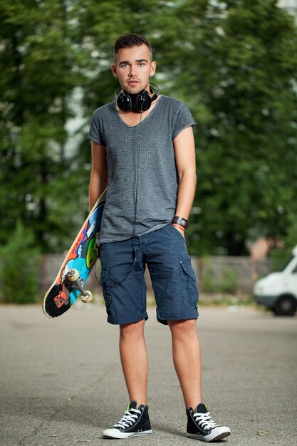 Beau mec avec des écouteurs et skateboard