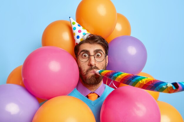 Beau mec entouré de ballons de fête posant