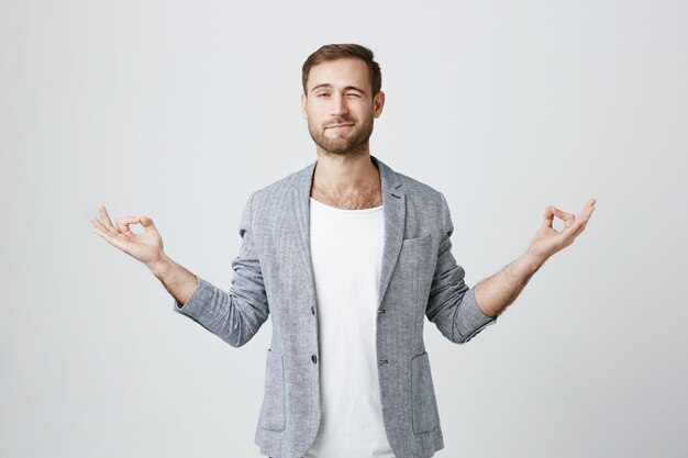 Beau mec essayant de méditer, jetant un œil pendant la séance de yoga