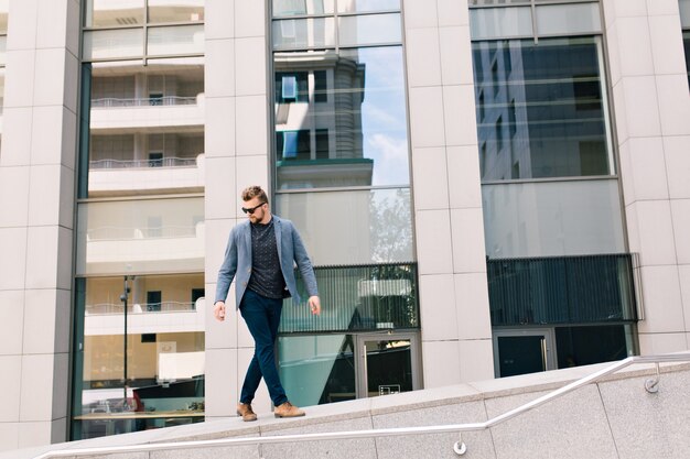 Beau mec en lunettes de soleil marchant dans la rue