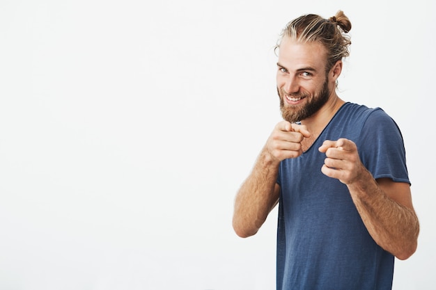 Beau mec mature avec barbe pointant vers la caméra avec l'index sur les deux mains avec une expression heureuse