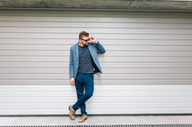 Beau mec posant sur un mur gris