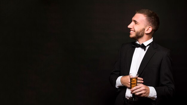 Beau mec souriant en veste avec un verre de boisson