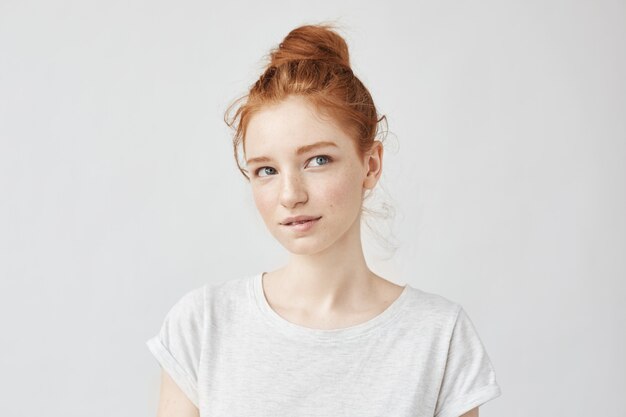 Beau modèle au gingembre avec chignon tendance rêvant de lèvre mordante.