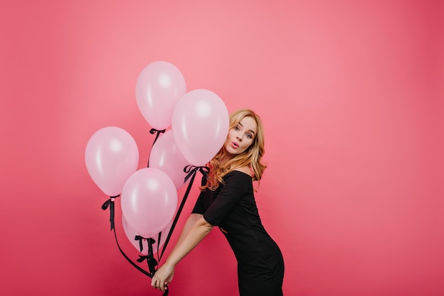 Beau modèle féminin blanc dansant à l'événement. joyeuse femme frisée caucasienne avec bouquet de ballons roses.