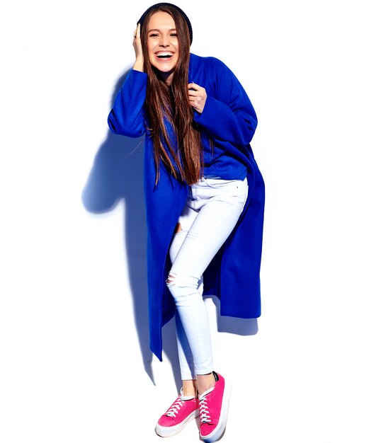 Beau modèle de femme brune hipster souriant en élégant manteau bleu isolé sur blanc. Toute la longueur