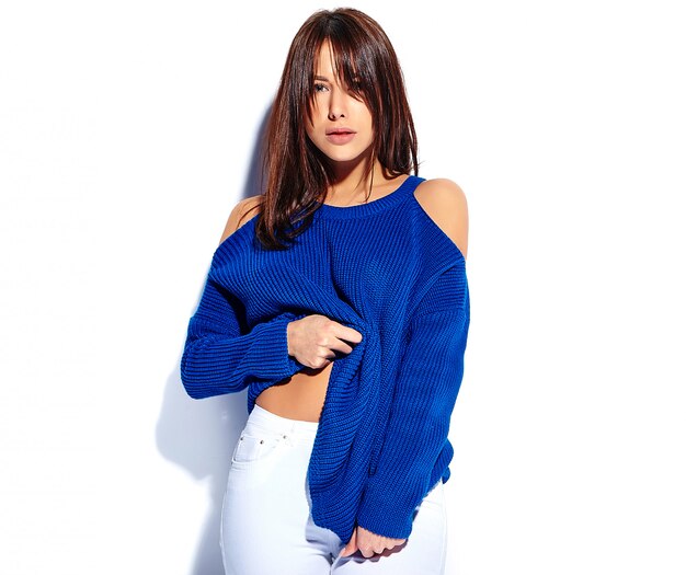 Beau modèle de femme brune hipster souriant tirant sur un élégant pull bleu d'été isolé sur fond blanc