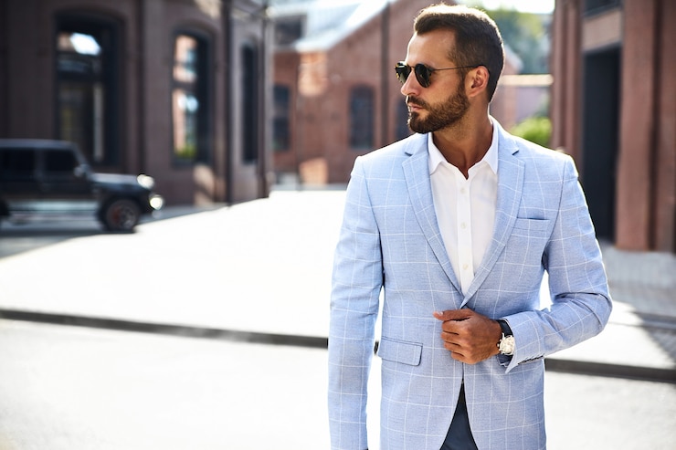 Photo gratuit beau modèle d'homme d'affaires de mode vêtu d'un élégant costume bleu posant sur la rue