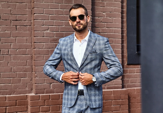 beau modèle d'homme d'affaires de mode vêtu d'un élégant costume à carreaux posant dans la rue