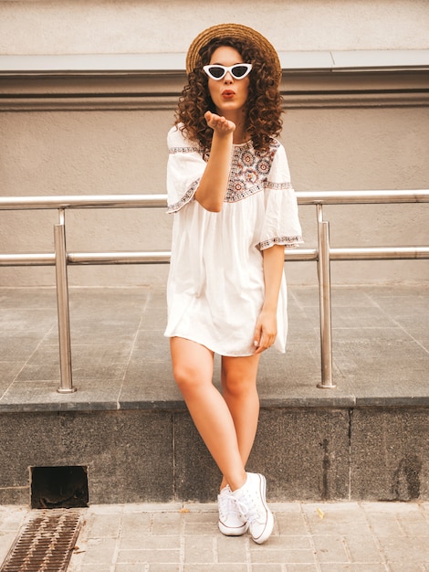 Photo gratuite beau modèle souriant avec une coiffure de boucles afro habillée en robe blanche d'été hipster.
