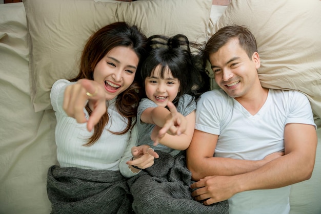Photo gratuite beau moment concept de famille avec fille et parent jouant ensemble dans une couverture sur un lit moelleux le matin