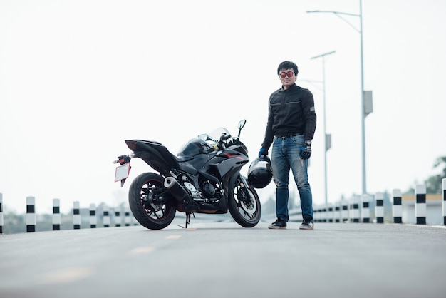 Beau motard avec casque dans les mains de la moto