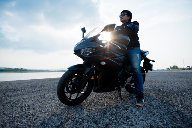 Beau motard avec casque dans les mains de la moto