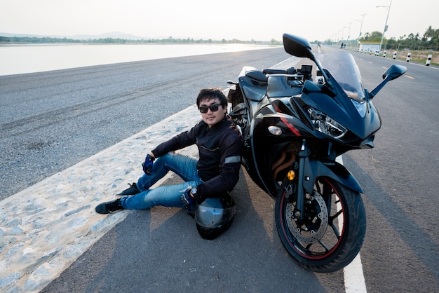 Beau motard avec casque dans les mains de la moto