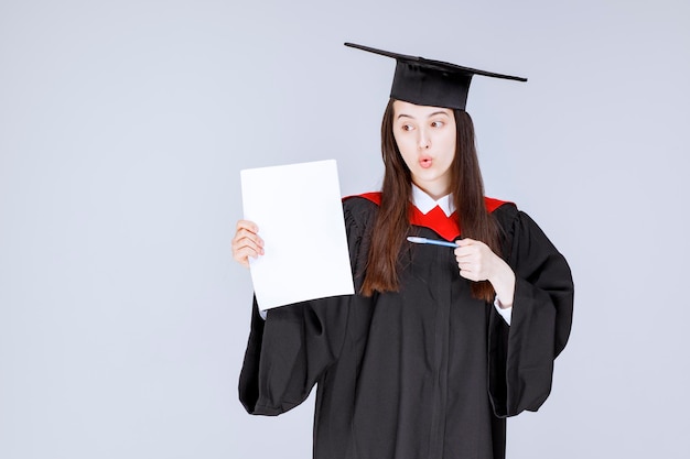 Beau papier étudiant féminin et stylo en mains posant. photo de haute qualité