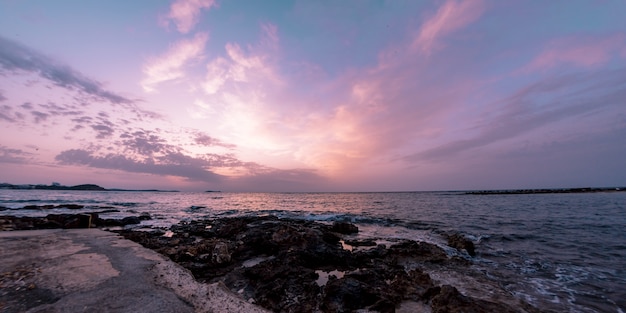 Beau paysage d'un bord de mer rocheux et d'une mer pendant le coucher du soleil