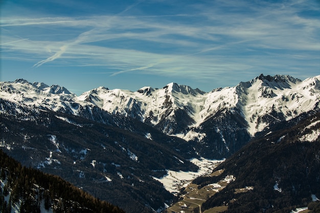 Beau paysage d'une gamme de montagnes rocheuses couvertes de neige sous un ciel nuageux