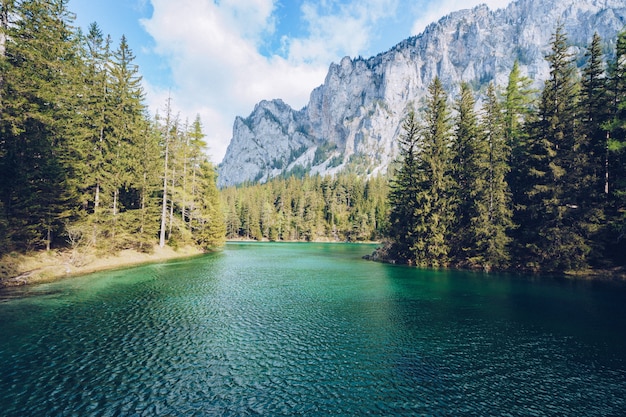 Beau paysage avec un lac dans une forêt et une incroyable haute montagne rocheuse