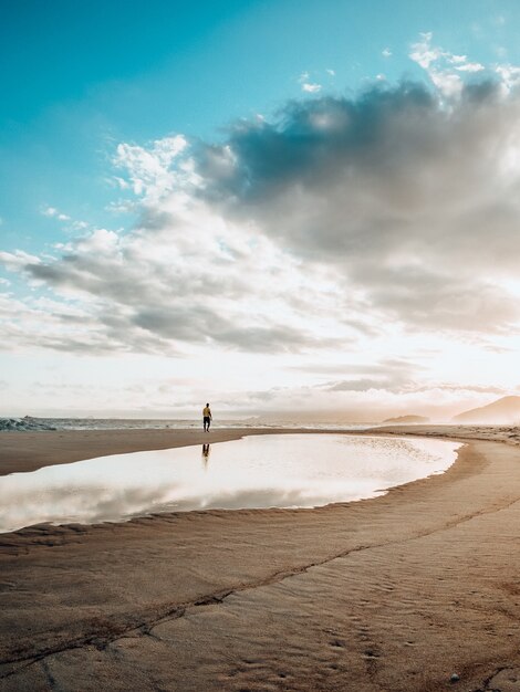 Beau paysage d'une personne seule exerçant pendant le coucher du soleil sur la plage avec un ciel nuageux