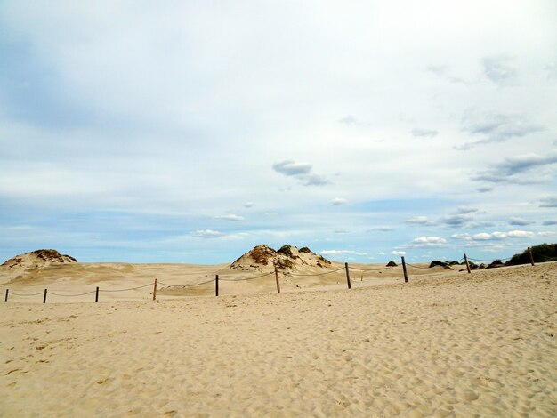 Beau paysage d'une plage de sable sous un ciel nuageux à Leba, Pologne