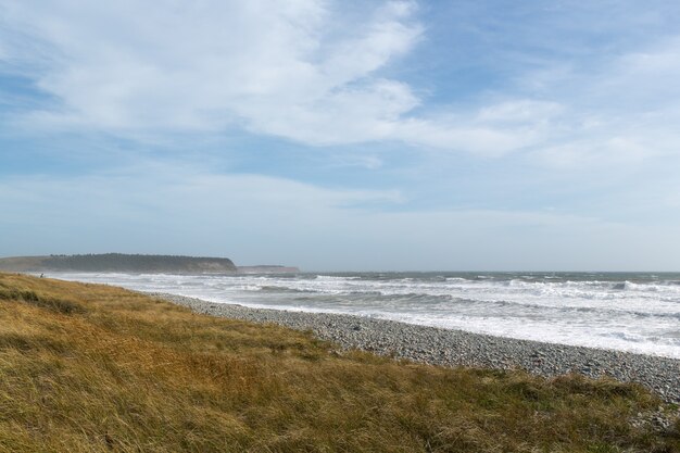 Beau paysage de vagues de l'océan se déplaçant vers le rivage sous le ciel nuageux