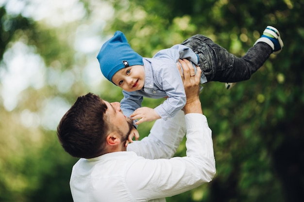 Beau père jetant un petit garçon contre le parc d'été Petit garçon portant des vêtements élégants et papa passant du temps ensemble en souriant et en s'amusant dehors dans la nature Concept parental heureux