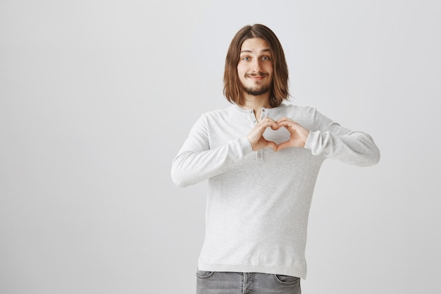 Beau petit ami montrant le geste du cœur, exprimer son amour et ses soins