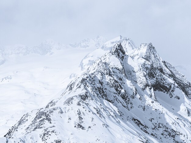 Beau plan large de montagnes couvertes de neige sous un ciel brumeux