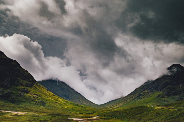 Beau plan large de montagnes vertes sous un ciel nuageux