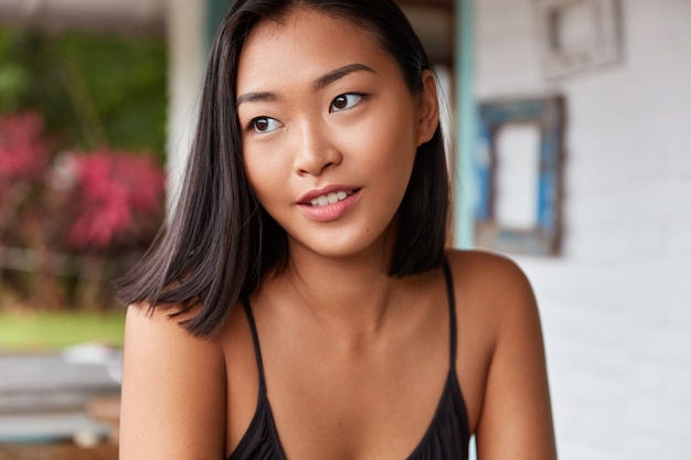 Beau portrait de femme chinoise avec une coiffure bobbed, pose dans une chambre confortable