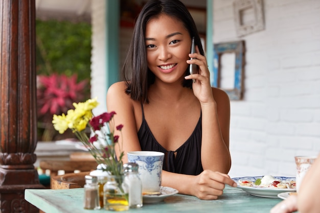 Beau portrait de femme chinoise parlant avec smartphone sur un café